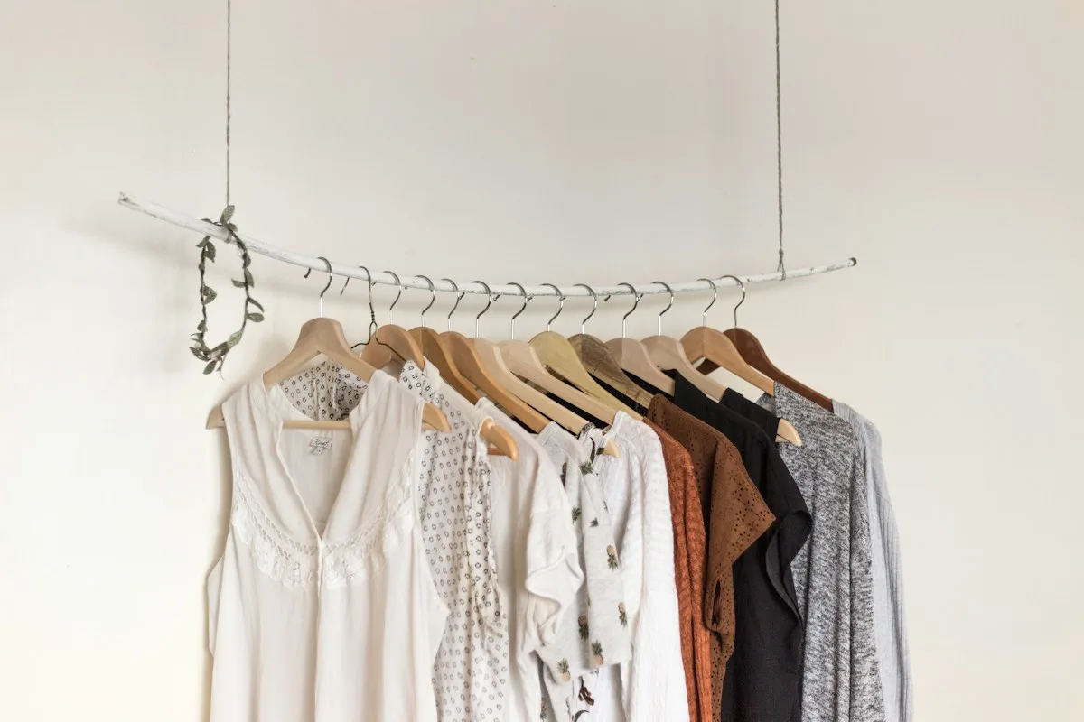 Perchero con blusas, camisas y vestidos en tonos neutros.